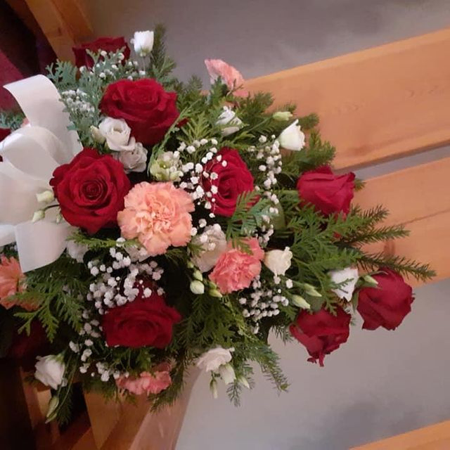 Punaisista, vaaleanpunaisista ja valkoisista kukista sidottu hautajaiskimppu