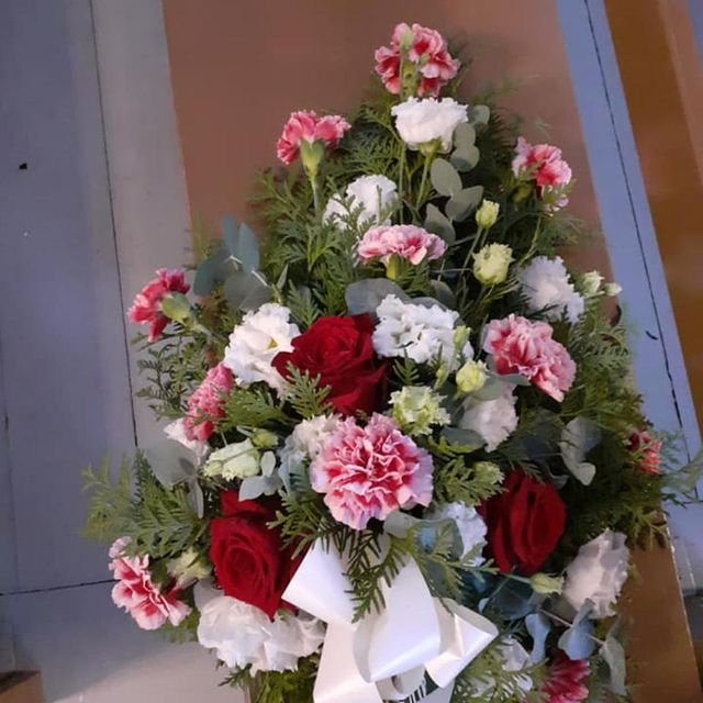 Punaisista ja valkoisista kukista sidottu hautajaiskimppu